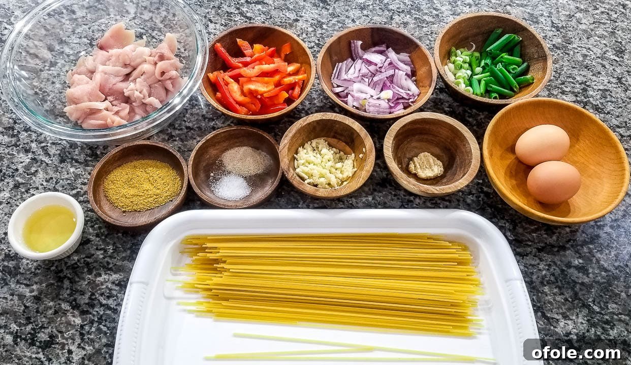 Assorted fresh ingredients for spaghetti stir fry, including raw chicken, eggs, bell peppers, onions, green onions, garlic, and ginger.