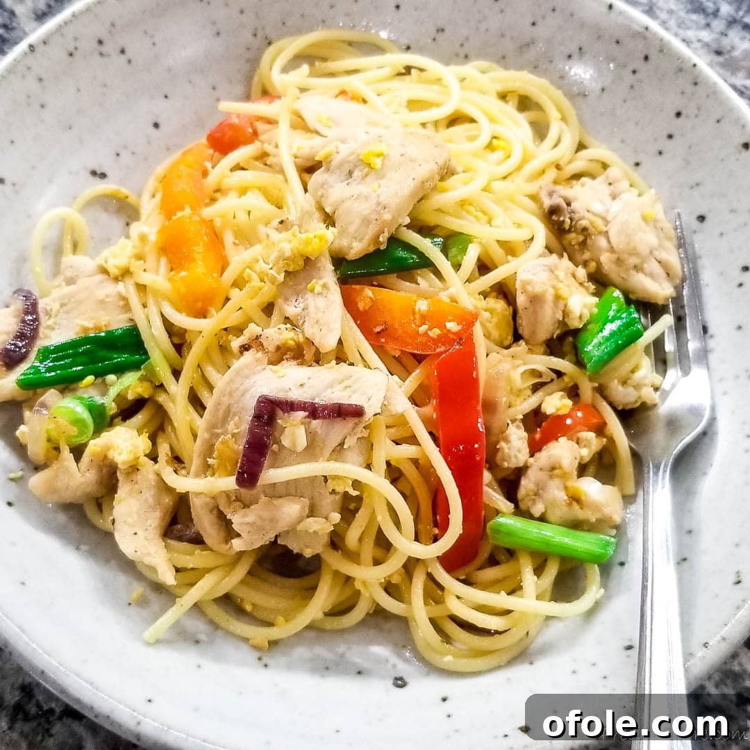 A perfectly plated serving of spaghetti stir fry, garnished with fresh green onions, ready to eat.