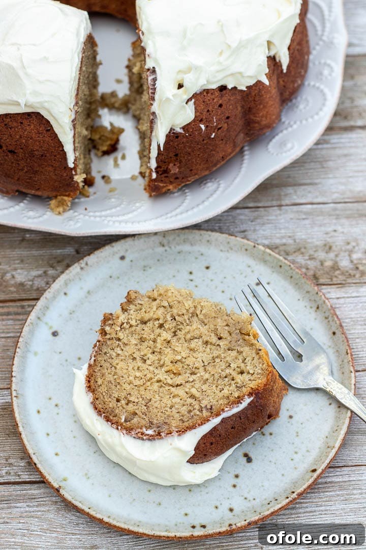 Moist Banana Bundt Cake 6 A delectable slice of banana bundt cake, topped with a generous swirl of creamy cream cheese frosting.
