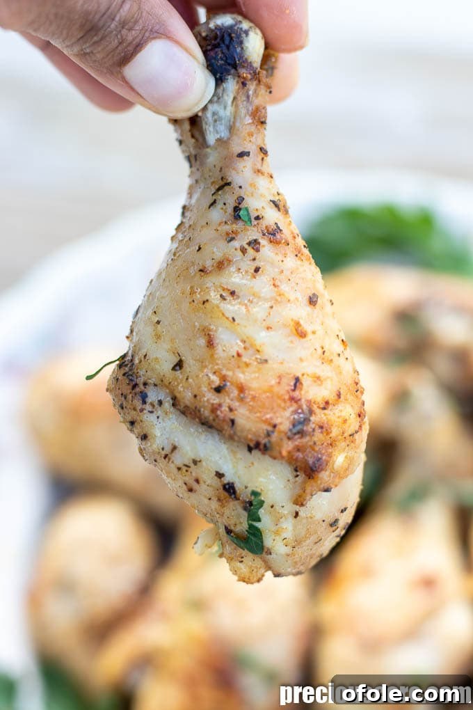 Extra Crispy Oven Baked Chicken Drumsticks 3 Hand holding a golden baked chicken drumstick, showing its crispy skin.