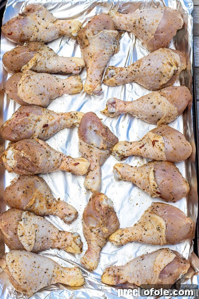 Extra Crispy Oven Baked Chicken Drumsticks 5 Seasoned chicken drumsticks arranged on a baking sheet, ready for the oven.