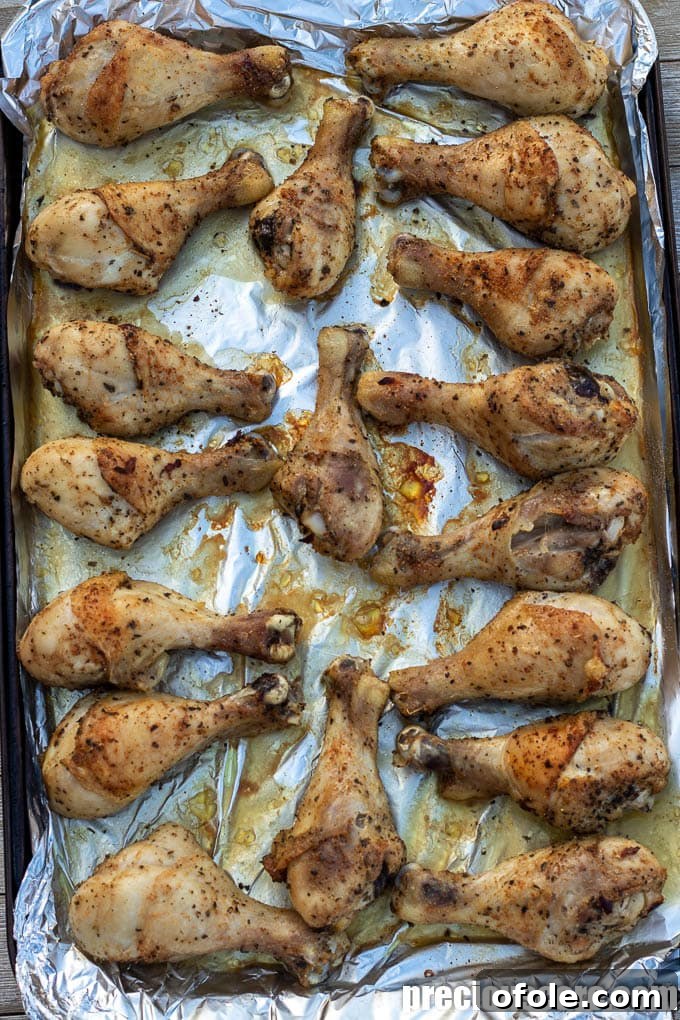 Extra Crispy Oven Baked Chicken Drumsticks 6 Freshly baked golden drumsticks still on the baking sheet, glistening and crispy.