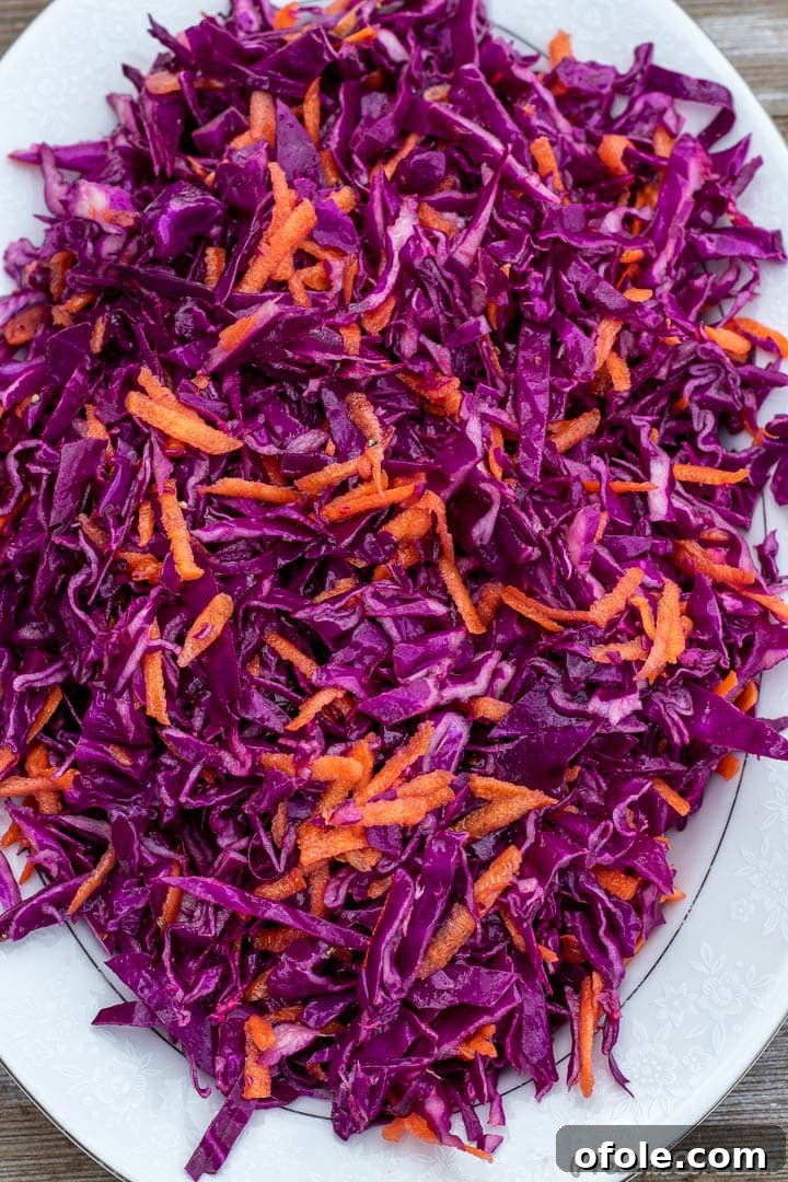 Close-up shot of purple cabbage slaw with finely shredded carrots and a glistening dressing