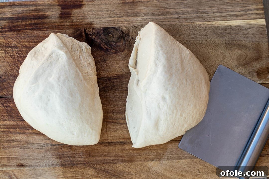 Two equal portions of sandwich bread dough on a chopping board, ready for shaping.