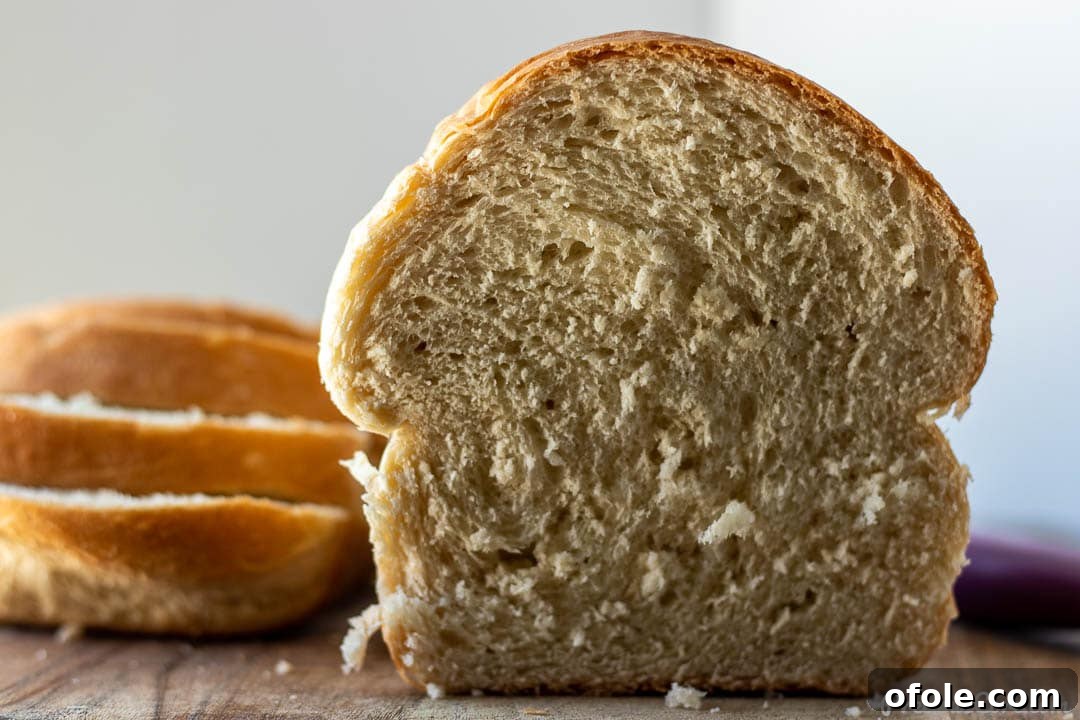 A half-loaf of homemade sandwich bread with several slices beside it, showcasing its perfect texture.