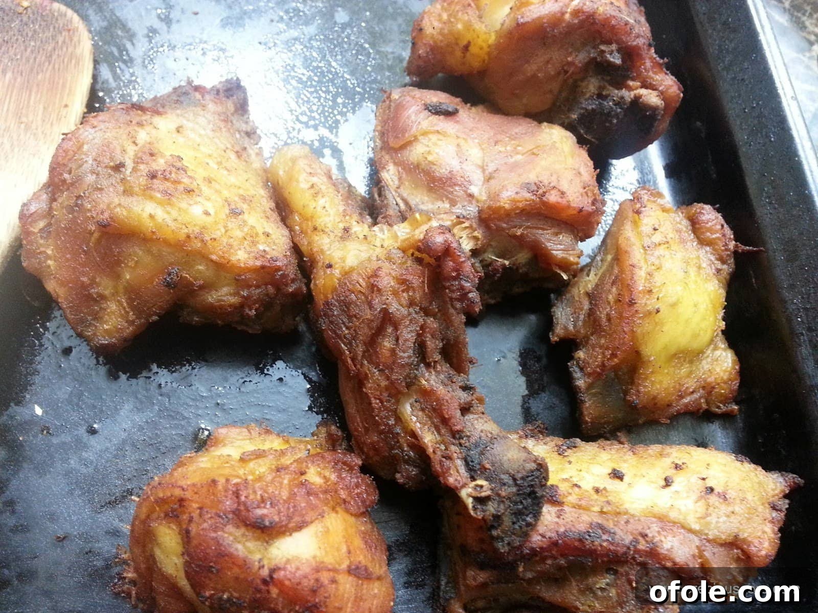 Close-up of freshly fried chicken, golden and crispy, garnished slightly on a plate.