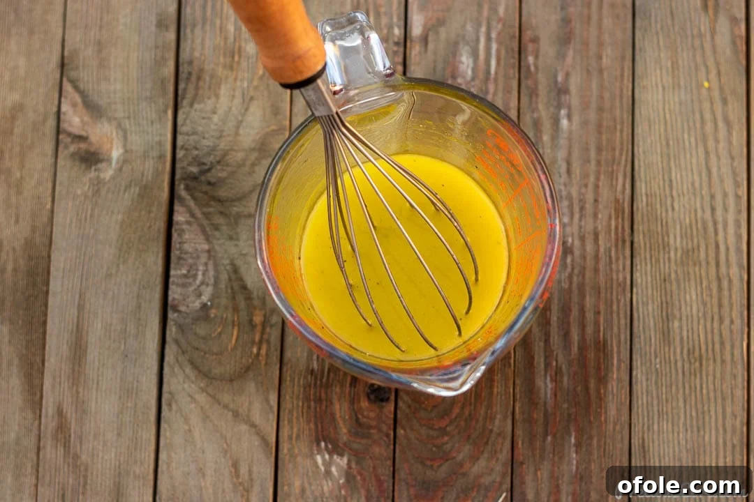 Crisp Green Salad 7 A clear liquid measuring cup containing a freshly prepared simple lemon vinaigrette, perfectly emulsified and ready to dress your salad.