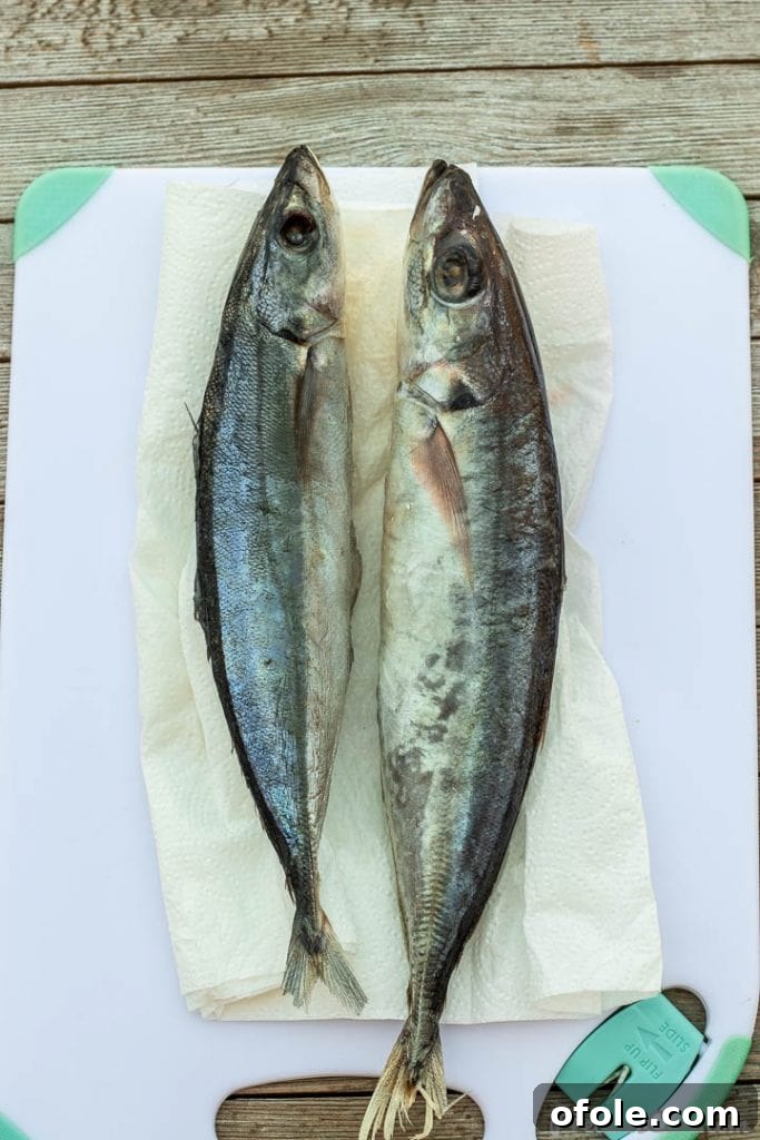 Two whole fish on a cutting board, ready for preparation