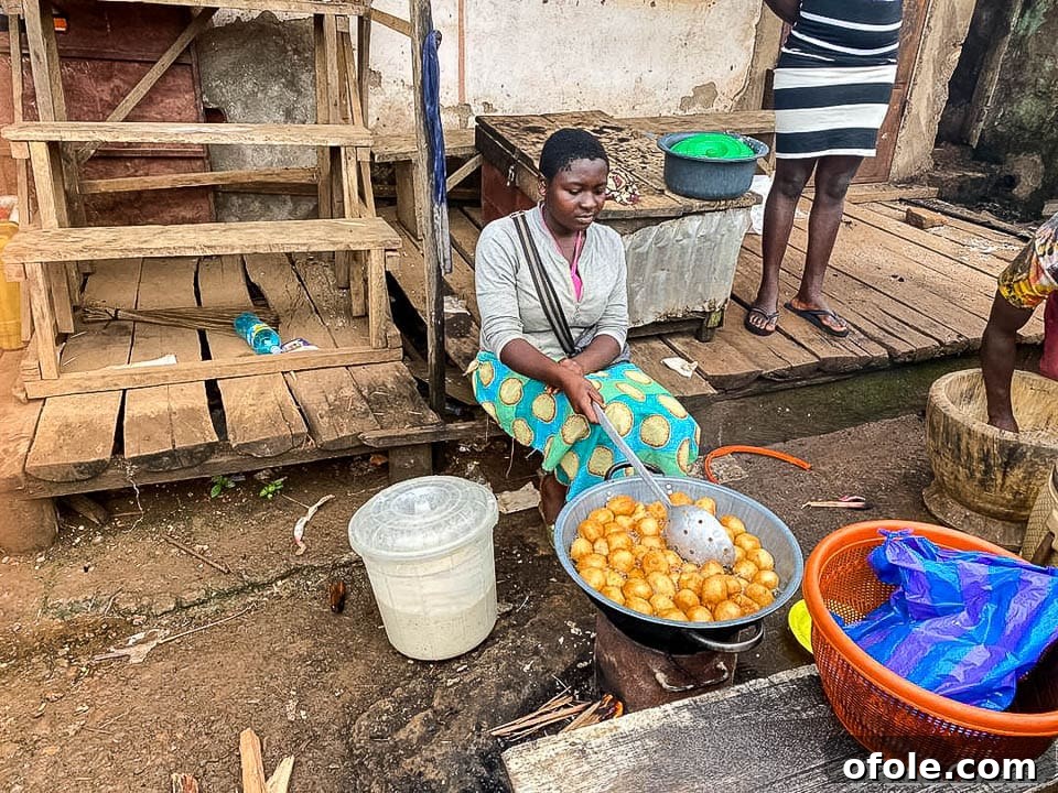 Woman frying golden Puff Puff in Cameroon, capturing street food culture