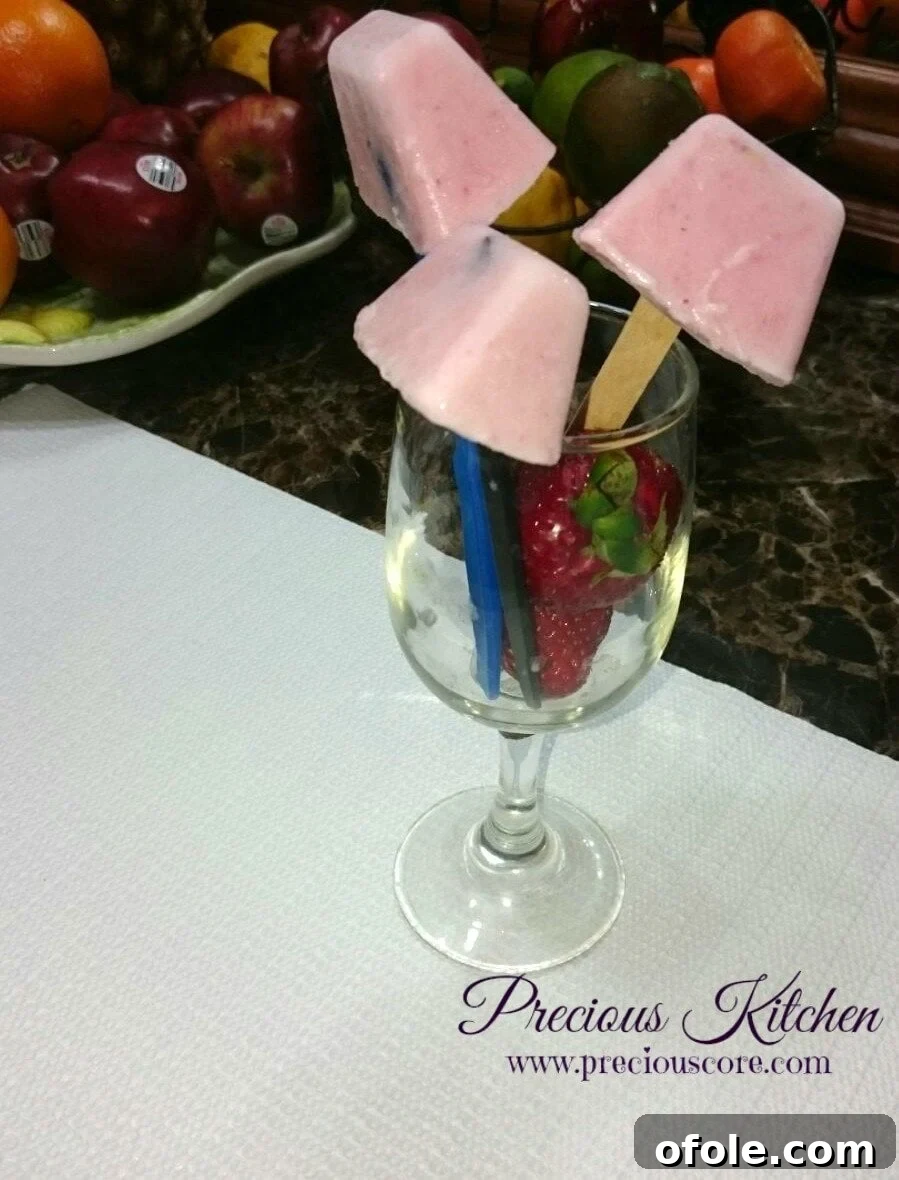 Close-up of a strawberry yogurt popsicle, showing its creamy texture and fresh fruit bits
