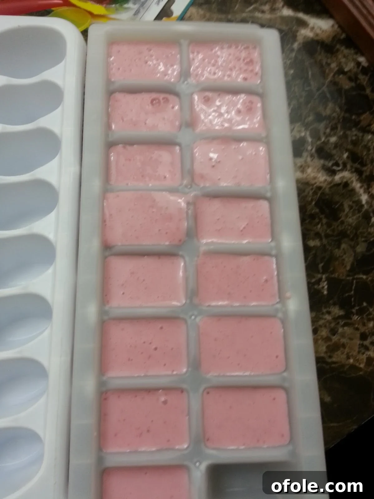 Popsicle mixture poured into ice cube trays, ready for initial freezing