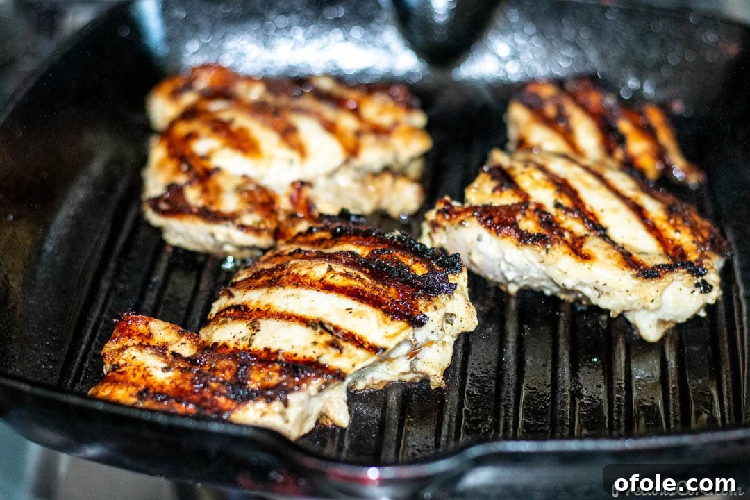 Succulent Grilled Boneless Chicken Thighs 5 Chicken thighs grilling in grill pan.