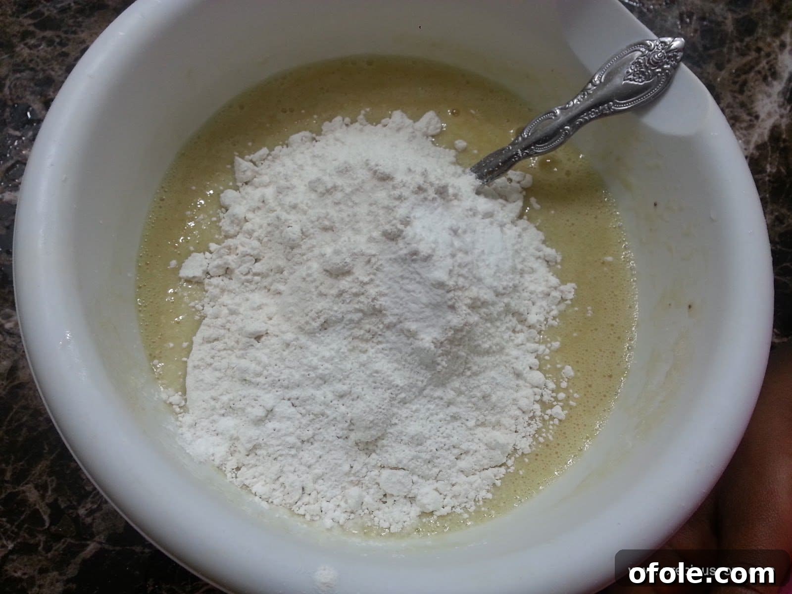 Pile of dry ingredients on top of wet ingredients in a mixing bowl.