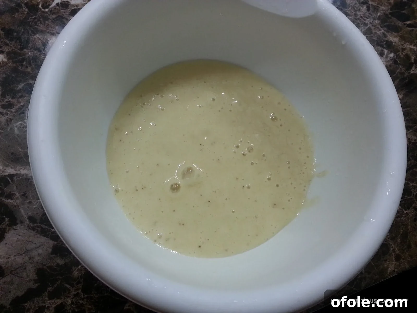 Banana and liquid mixture in a mixing bowl, ready for eggs.
