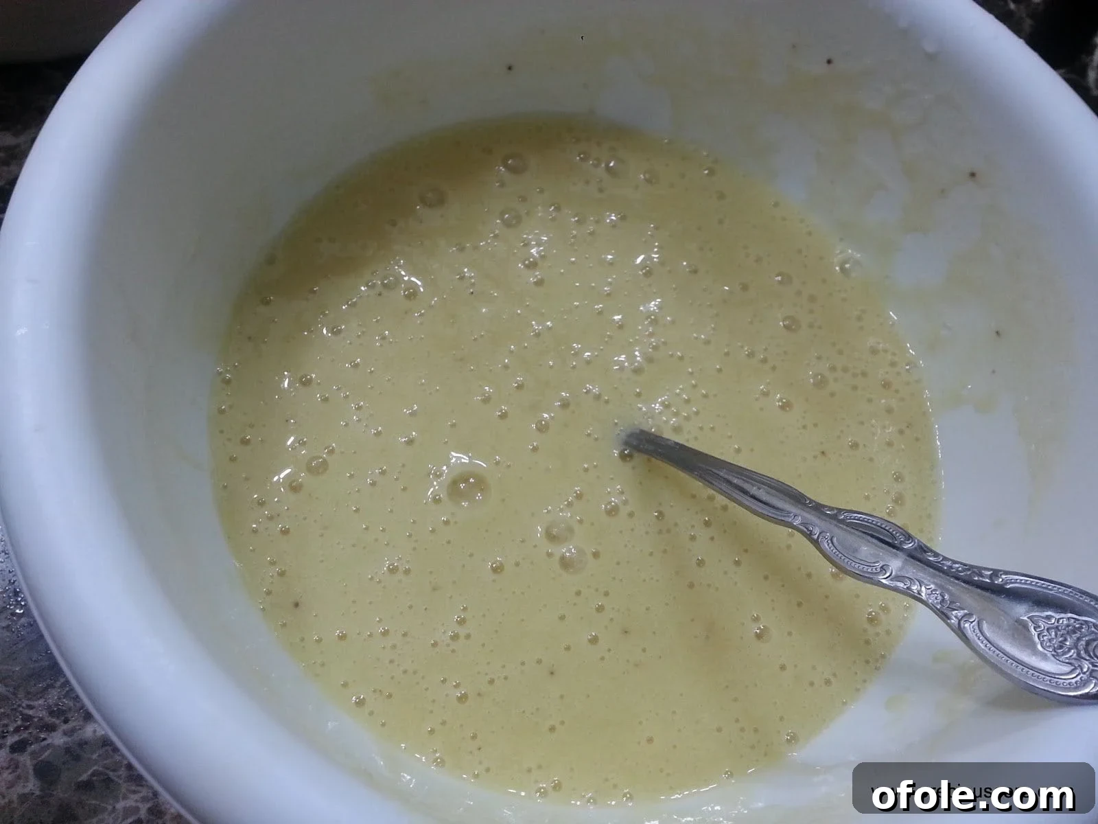 Spoon mixing wet ingredients in a bowl.