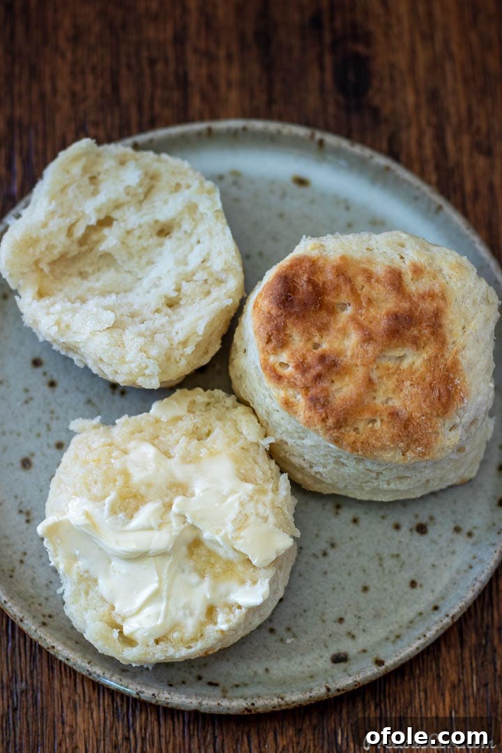 A stack of warm cream cheese biscuits, one topped with a generous dollop of butter.