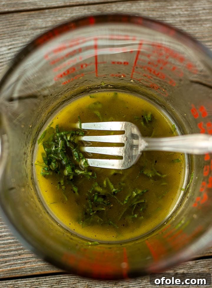Zesty Cucumber Tomato Onion Medley 5 Freshly prepared basil lemon salad dressing in a clear measuring cup.