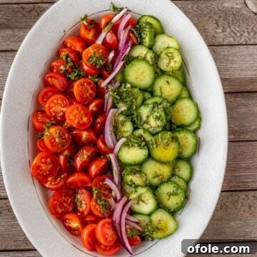 Cucumber Tomato and Onion Salad on a platter, garnished beautifully.