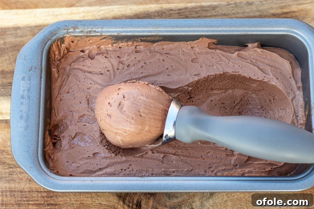 A large scoop of frozen chocolate ice cream resting in the loaf pan, indicating it's ready to be served and enjoyed.
