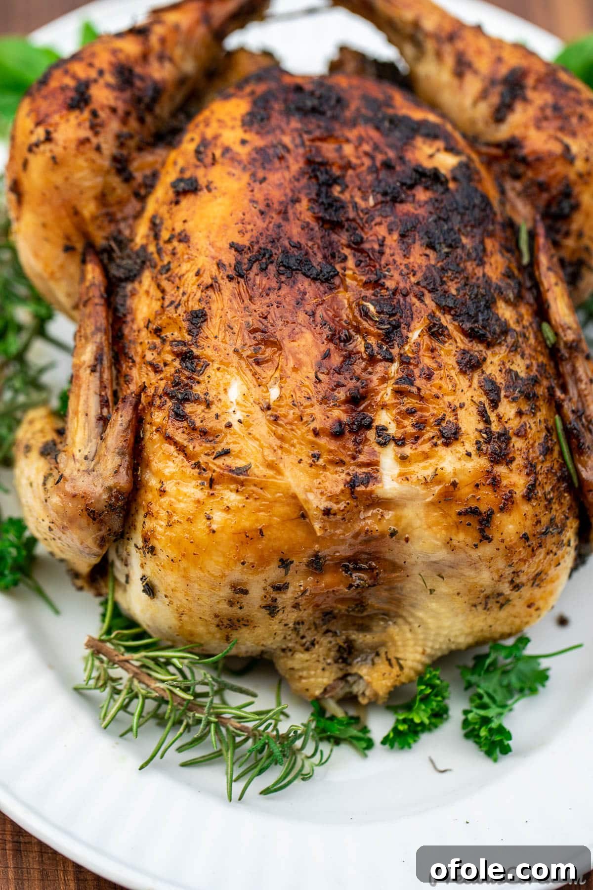 Savory Herb Roasted Chicken 5 Whole herb roasted chicken on a platter, beautifully garnished with fresh herbs and lemon slices for a vibrant presentation.