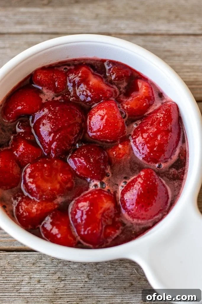 A bowl filled with vibrant homemade strawberry sauce, perfect for topping pancakes or waffles.