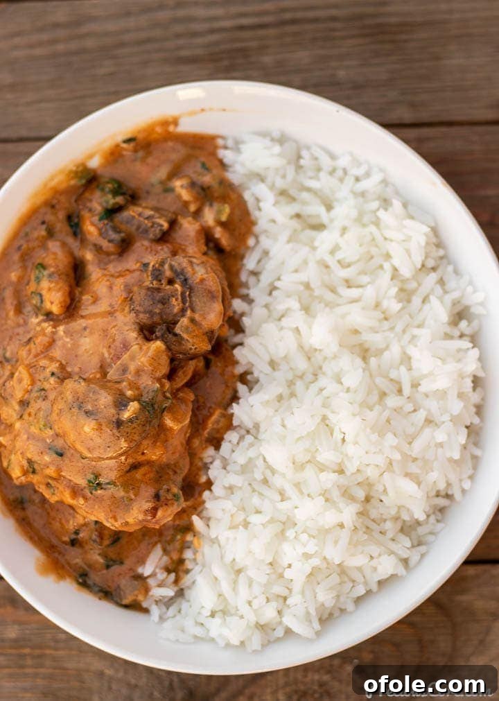 Soulful African Peanut Chicken Stew 2 African chicken peanut stew and rice in bowl, garnished with fresh herbs.