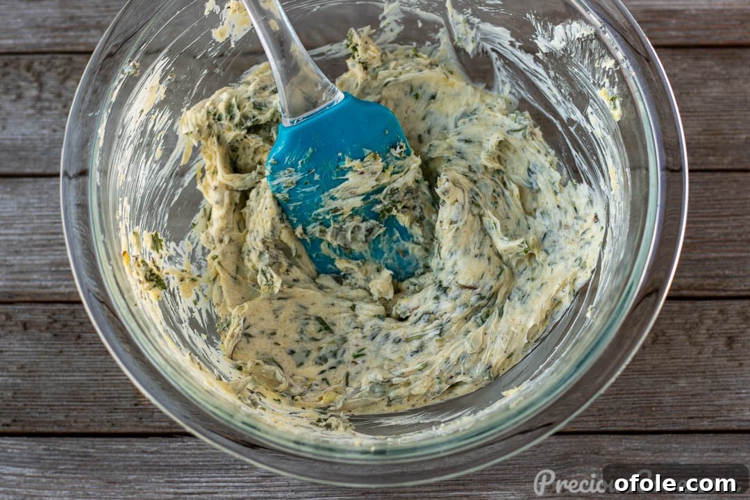 Close-up of freshly made garlic herb butter in a glass bowl, showcasing the herbs and minced garlic, ready to be applied to the turkey.