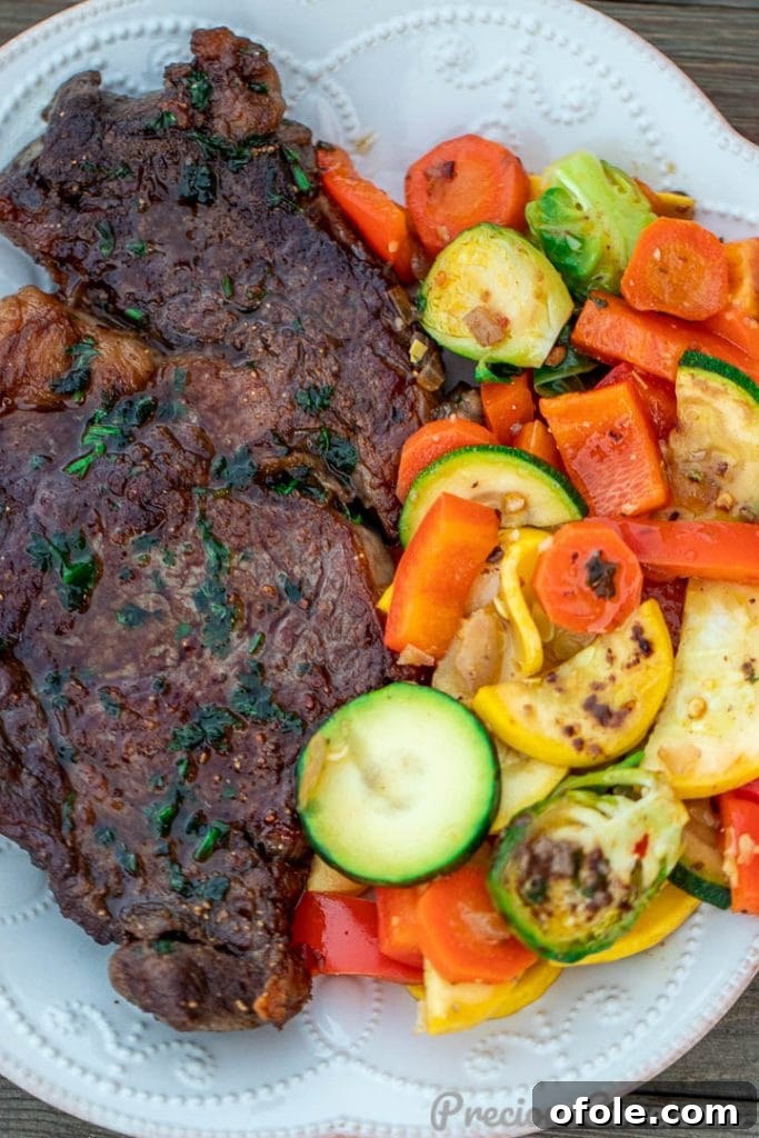 Pan Seared Ribeye with Veggies A beautifully plated pan-seared ribeye steak, sliced, and served with a vibrant side of sautéed vegetables on a white plate.