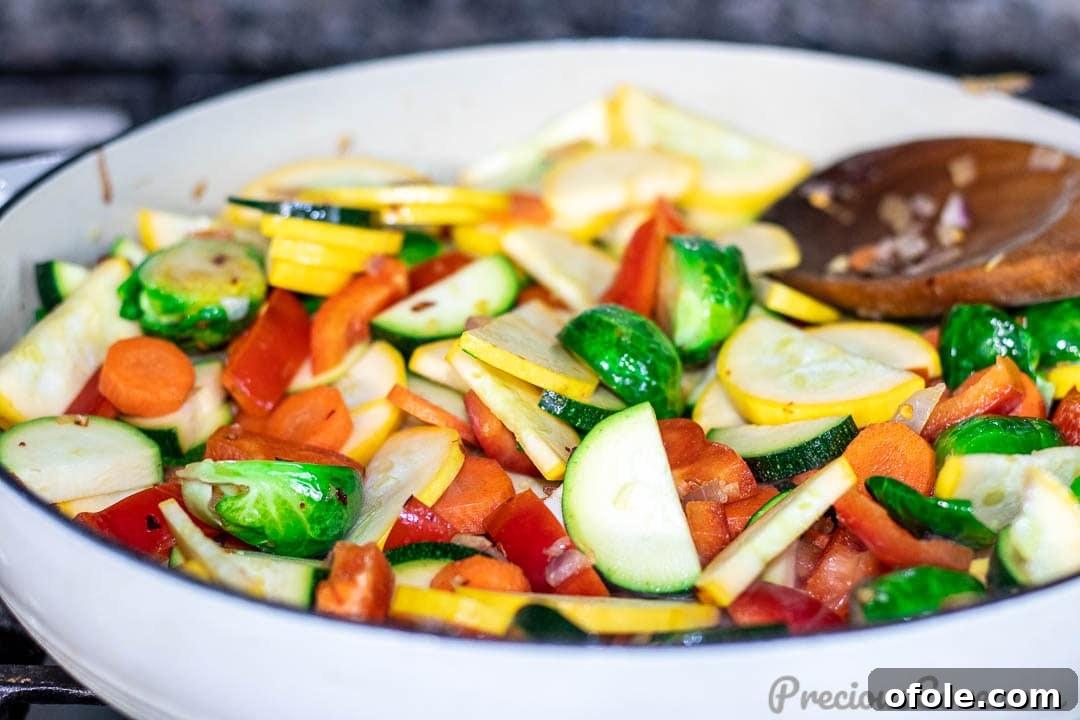 All chosen vegetables, including bell peppers, zucchini, and carrots, combined in the pan and actively sautéing, creating a colorful and dynamic medley.