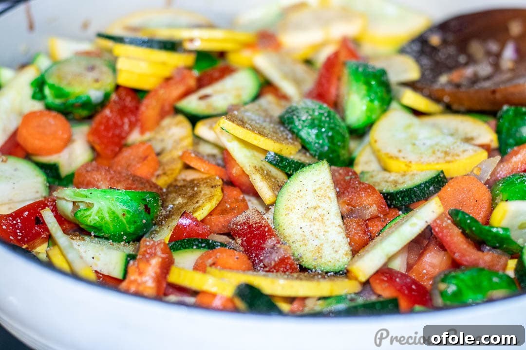 Sautéed vegetables in a pan, beautifully seasoned and steaming hot, ready to be transferred to a serving dish.
