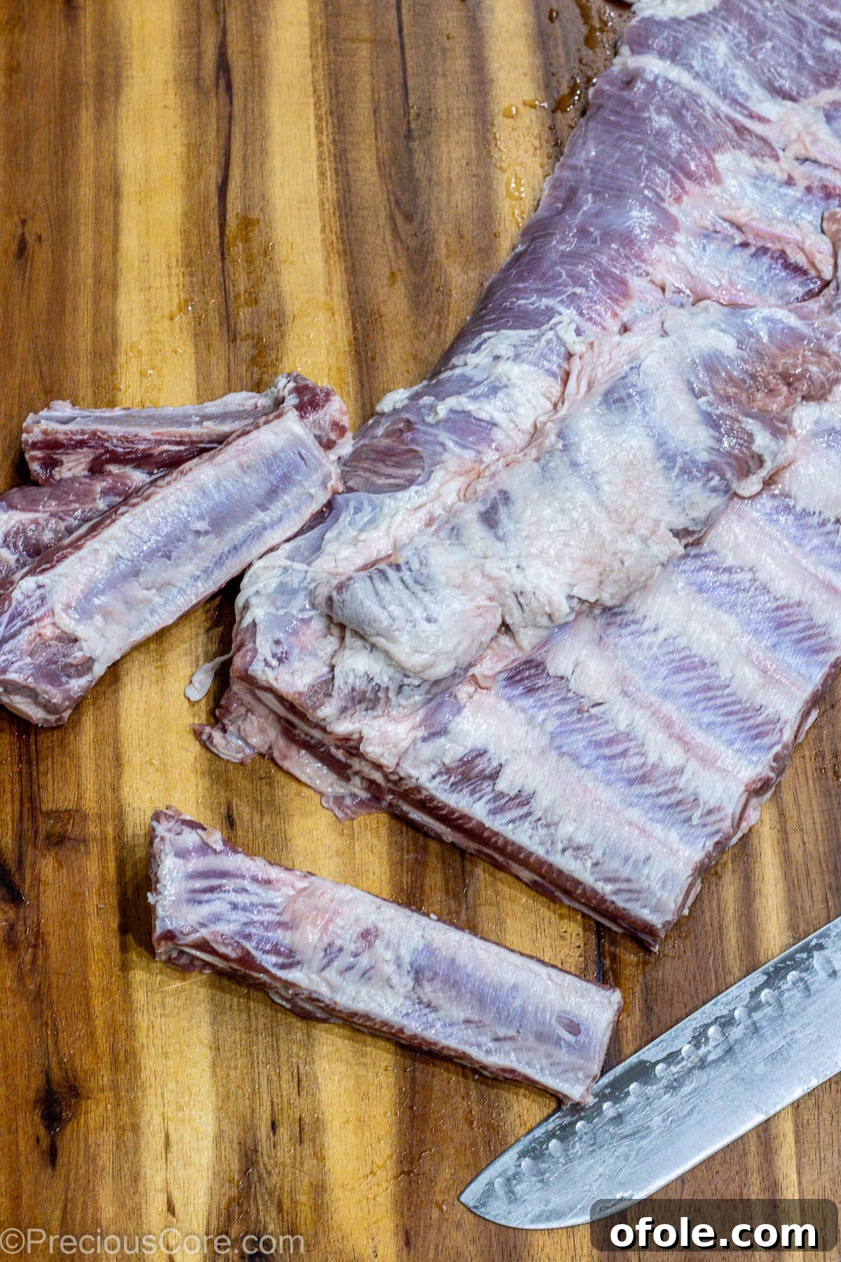 A full rack of ribs meticulously cut into individual portions, arranged on a cutting board, ready for seasoning and baking.