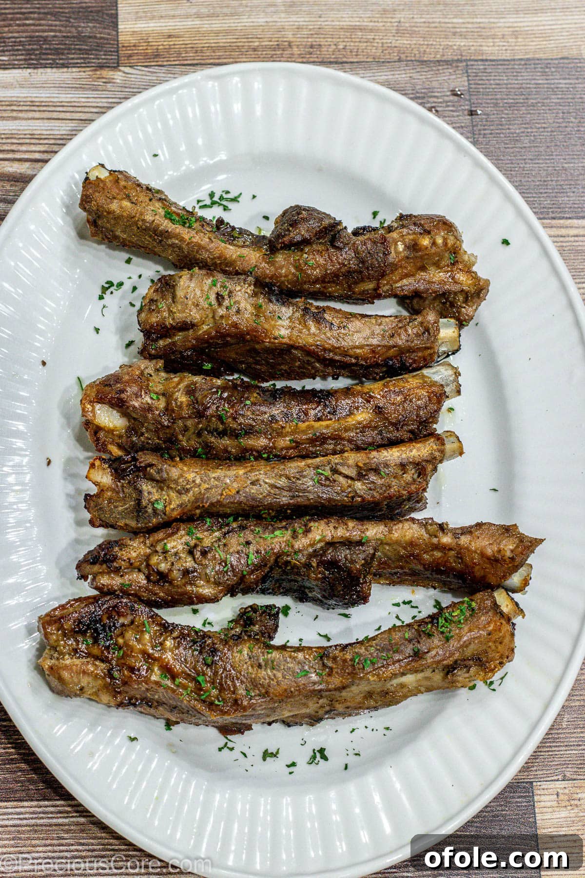 A generous serving of beautifully broiled dry rub ribs, piled high on a rustic serving tray, showcasing their mouth-watering crust.