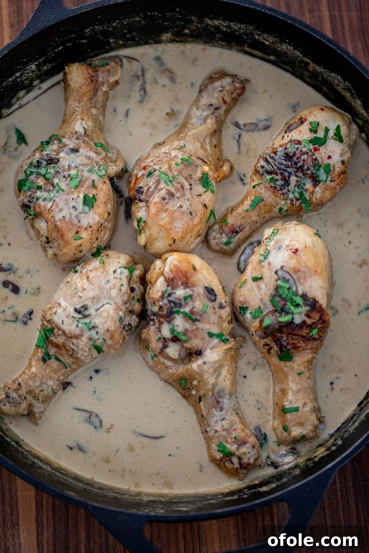 Chicken drumsticks in creamy sauce in a cast iron skillet