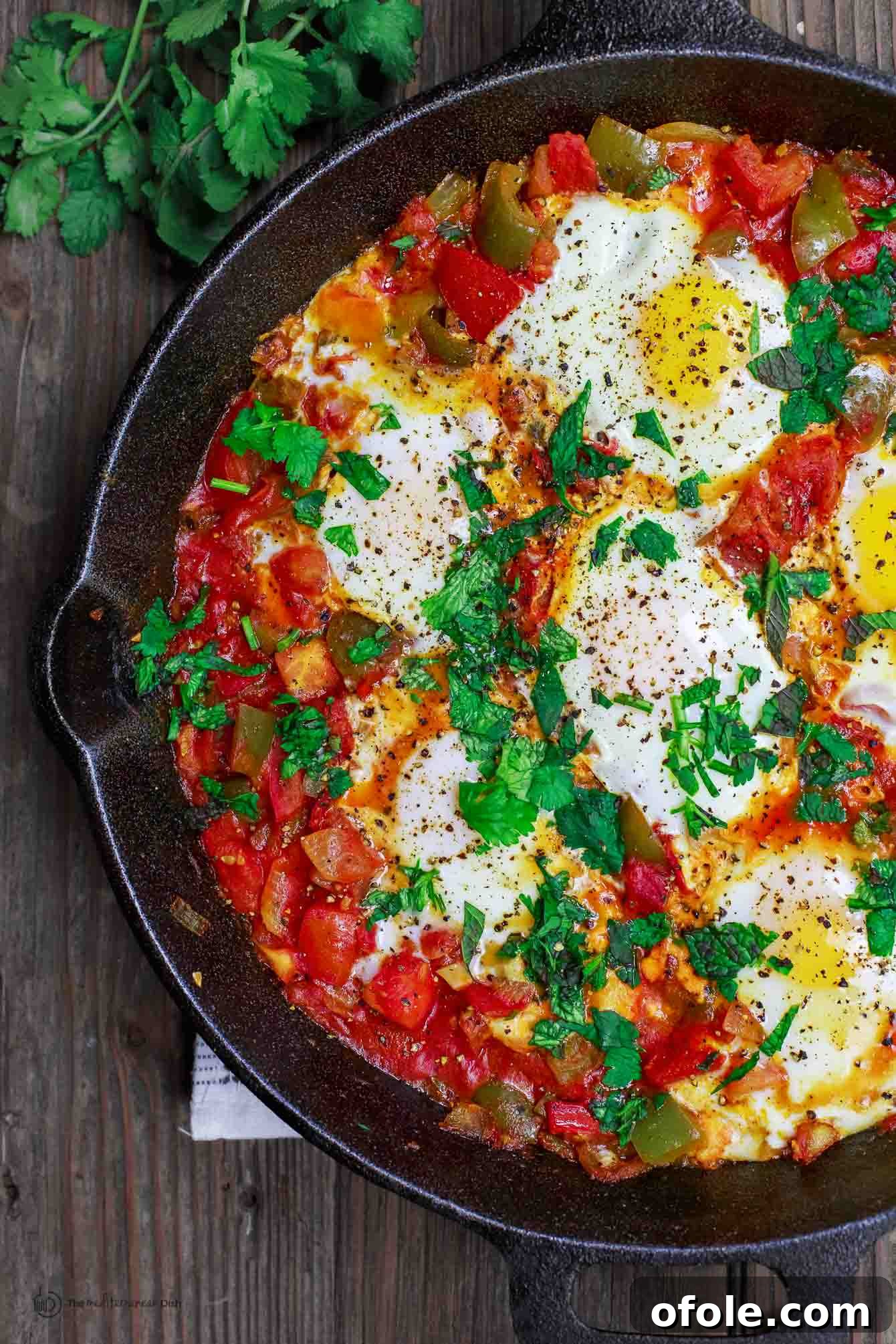 Discover Africa: 20 Irresistible Dinner Recipes 29 Shakshuka with perfectly poached eggs in a rich tomato sauce, served in a cast iron skillet.