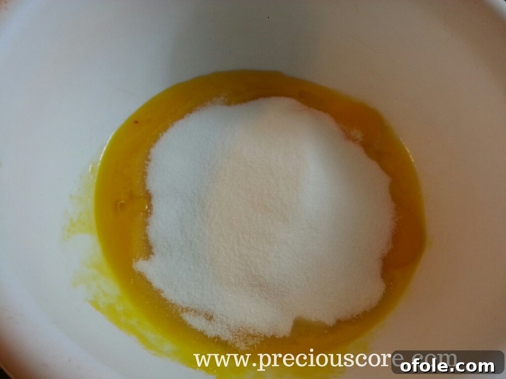 Sugar poured into egg yolks in a mixing bowl