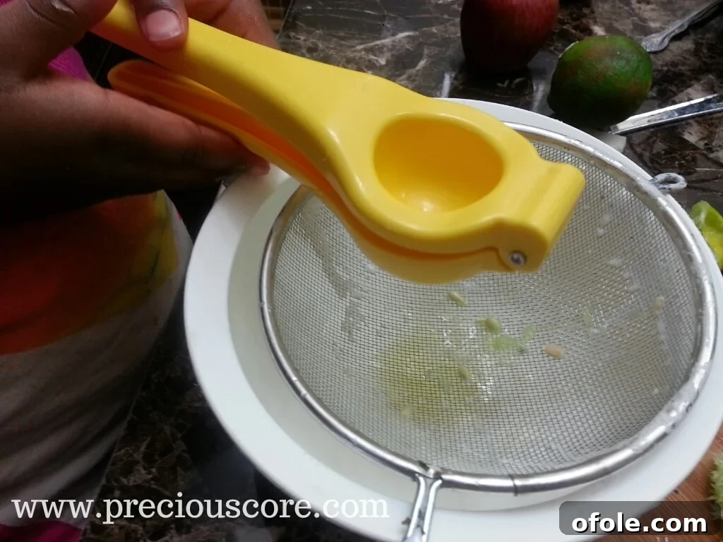 Squeezing key lime juice by hand into a strainer over a bowl