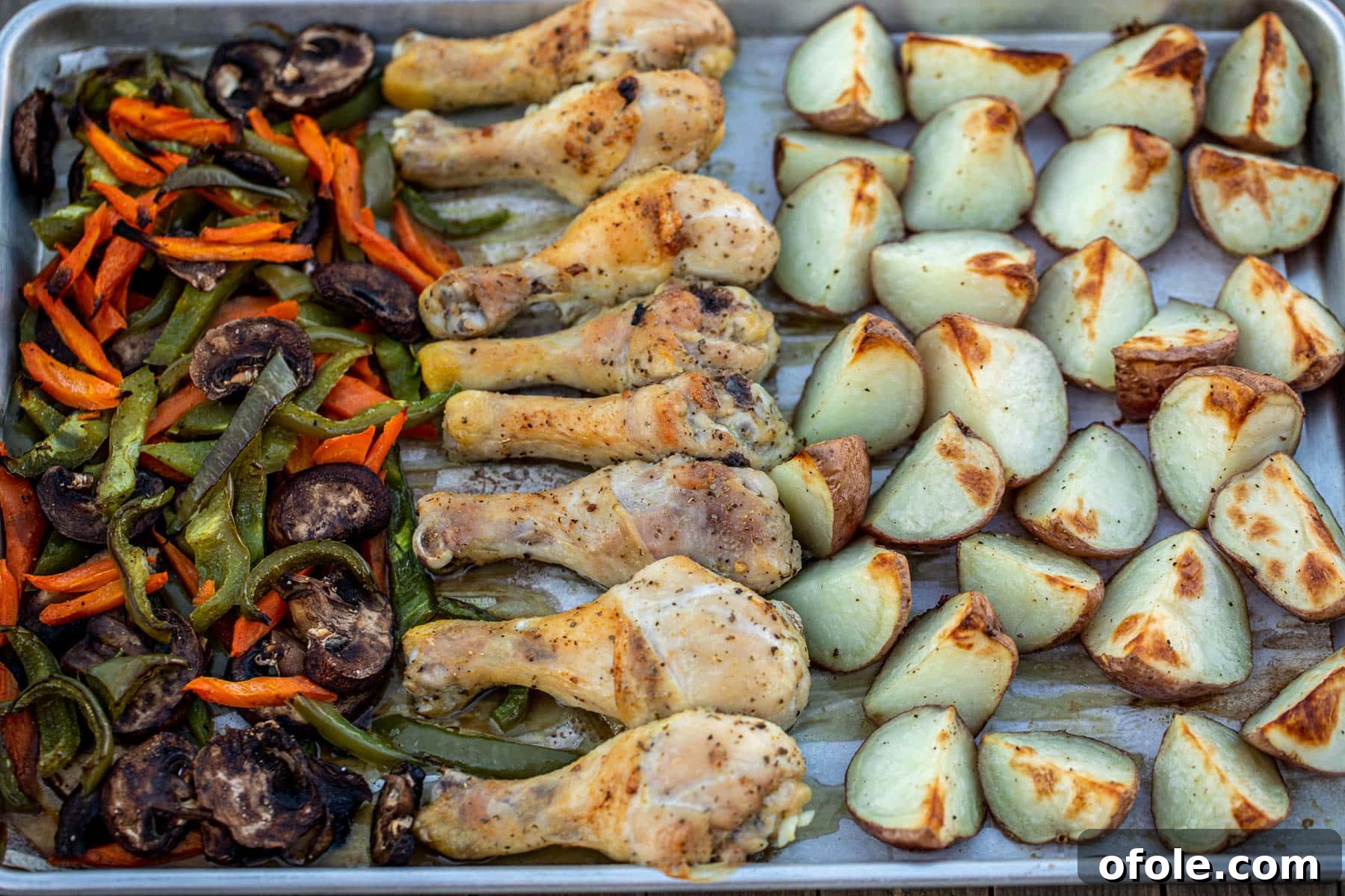 One-Pan Roasted Chicken, Potatoes, and Vegetables 6 A wide, landscape shot of the fully baked one-pan chicken, potatoes, and veggies, golden and steaming hot, just out of the oven.