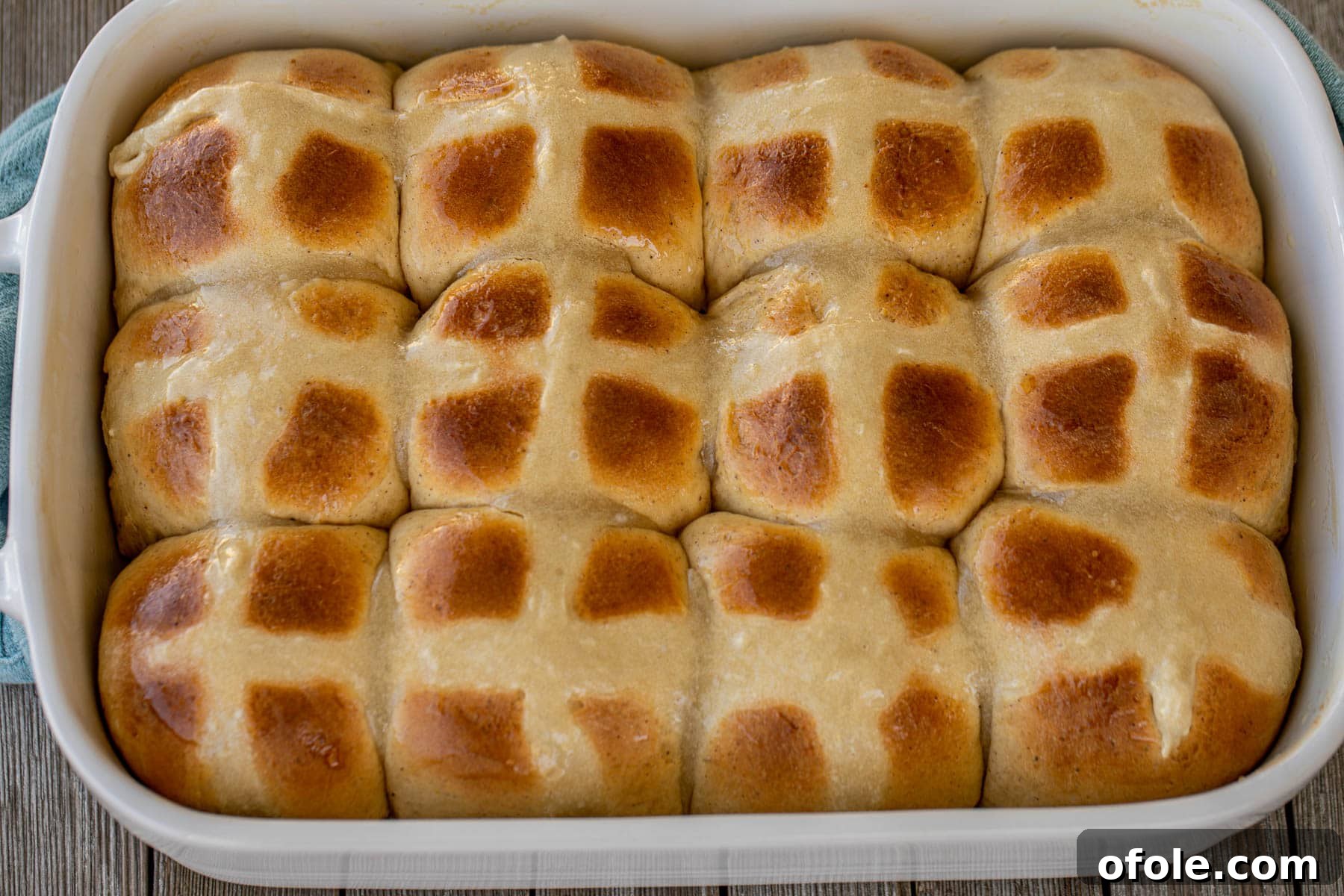 The Ultimate Hot Cross Buns 6 A beautiful landscape shot of several favorite hot cross buns in a baking tray, showcasing their fluffy texture.