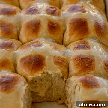 The Ultimate Hot Cross Buns 7 Hot Cross Buns in a baking dish with one removed