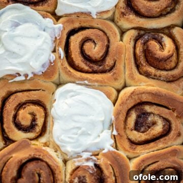 Cinnamon rolls in a pan, some of the rolls frosted with cream cheese frosting