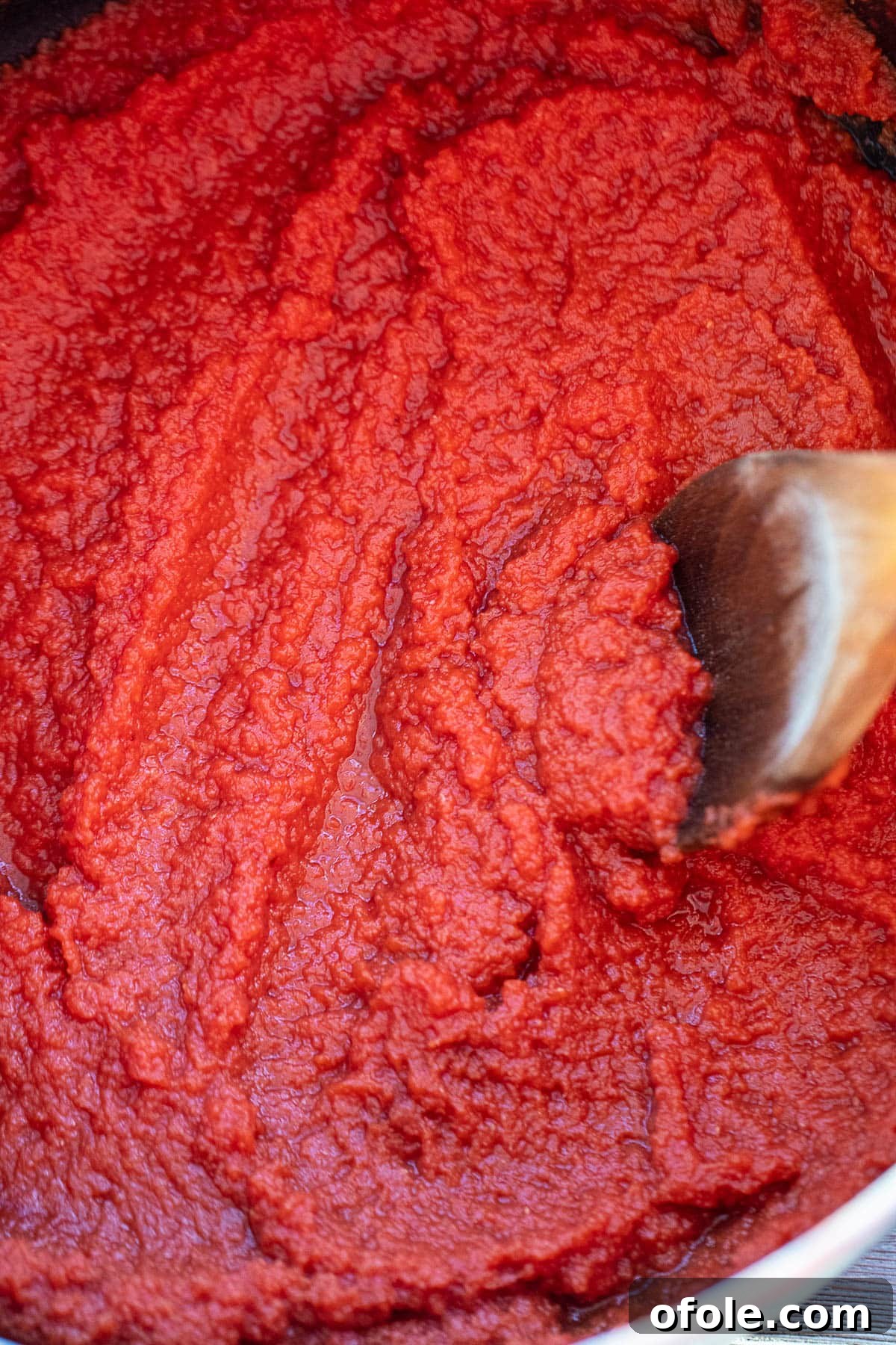 Slow-Simmered Homemade Tomato Paste 8 Tomato puree reducing and thickening in a large pot on the stovetop.