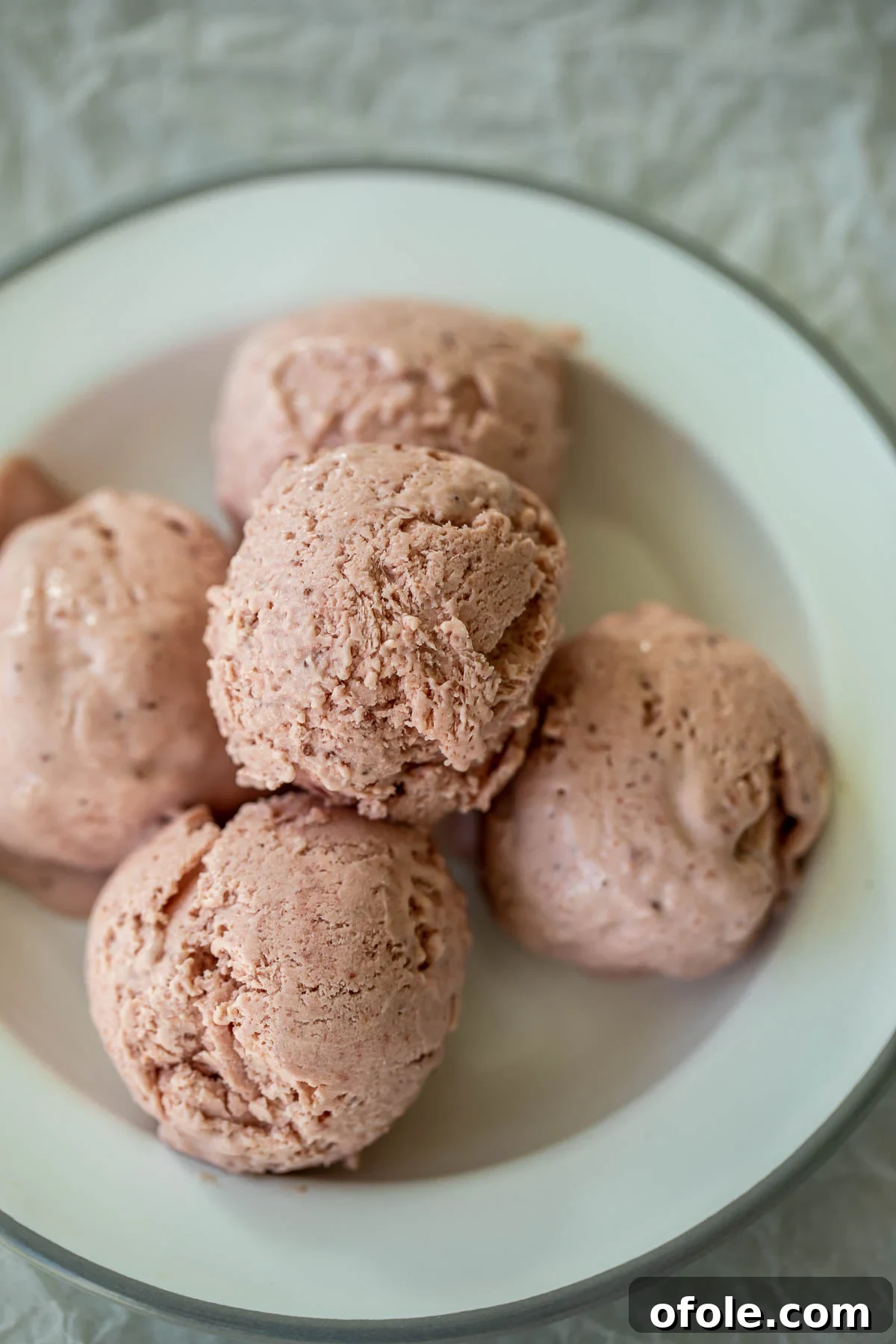 Easy No Churn Strawberry Ice Cream 2 Scoops of vibrant No-Churn Strawberry Ice Cream on a plate, garnished with fresh strawberries