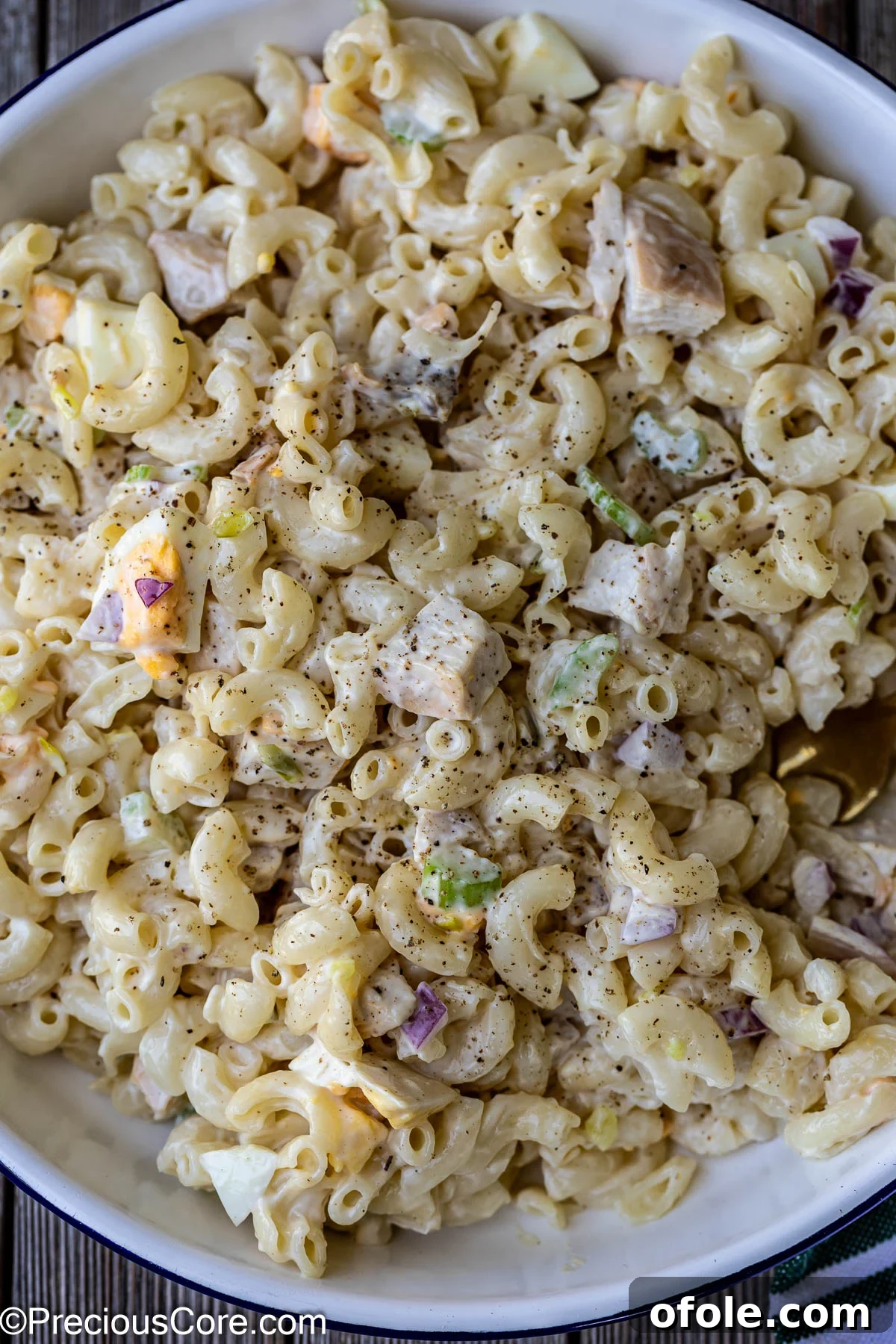 Creamy macaroni salad with chicken in a white bowl.