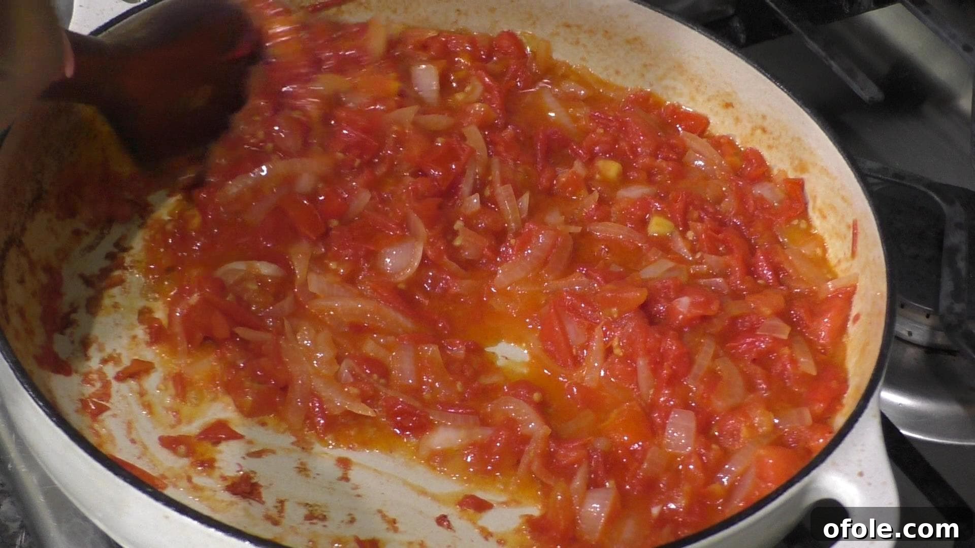 Diced tomatoes and onions simmering in a pot, forming the rich base of the stew.