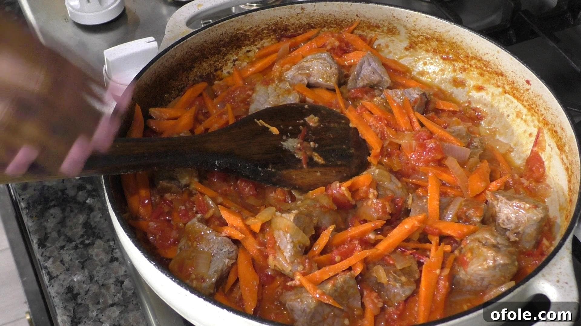 A pot filled with carrots and cooked beef simmering in the tomato and onion base.