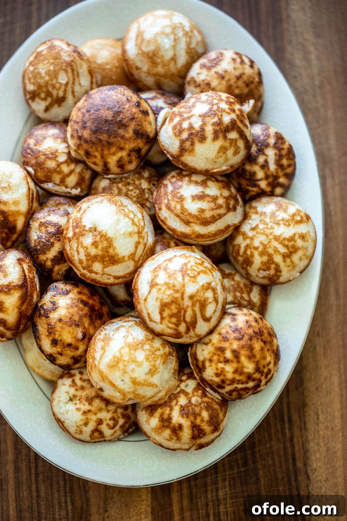 East Africa's Sweet Secret: Vitumbua Coconut Rice Pancakes 2 Several dozen cooked Vitumbua on a white tray, showcasing their perfect golden-brown color and round shape.