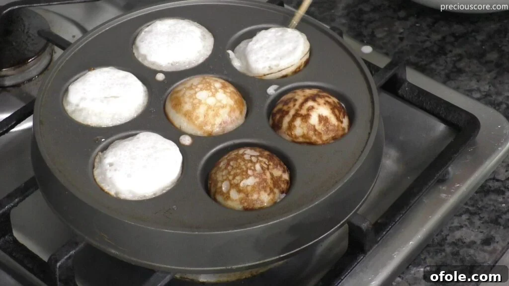 East Africa's Sweet Secret: Vitumbua Coconut Rice Pancakes 7 Cooking Vitumbua on an Aebleskiver pan, with batter filling each cavity.