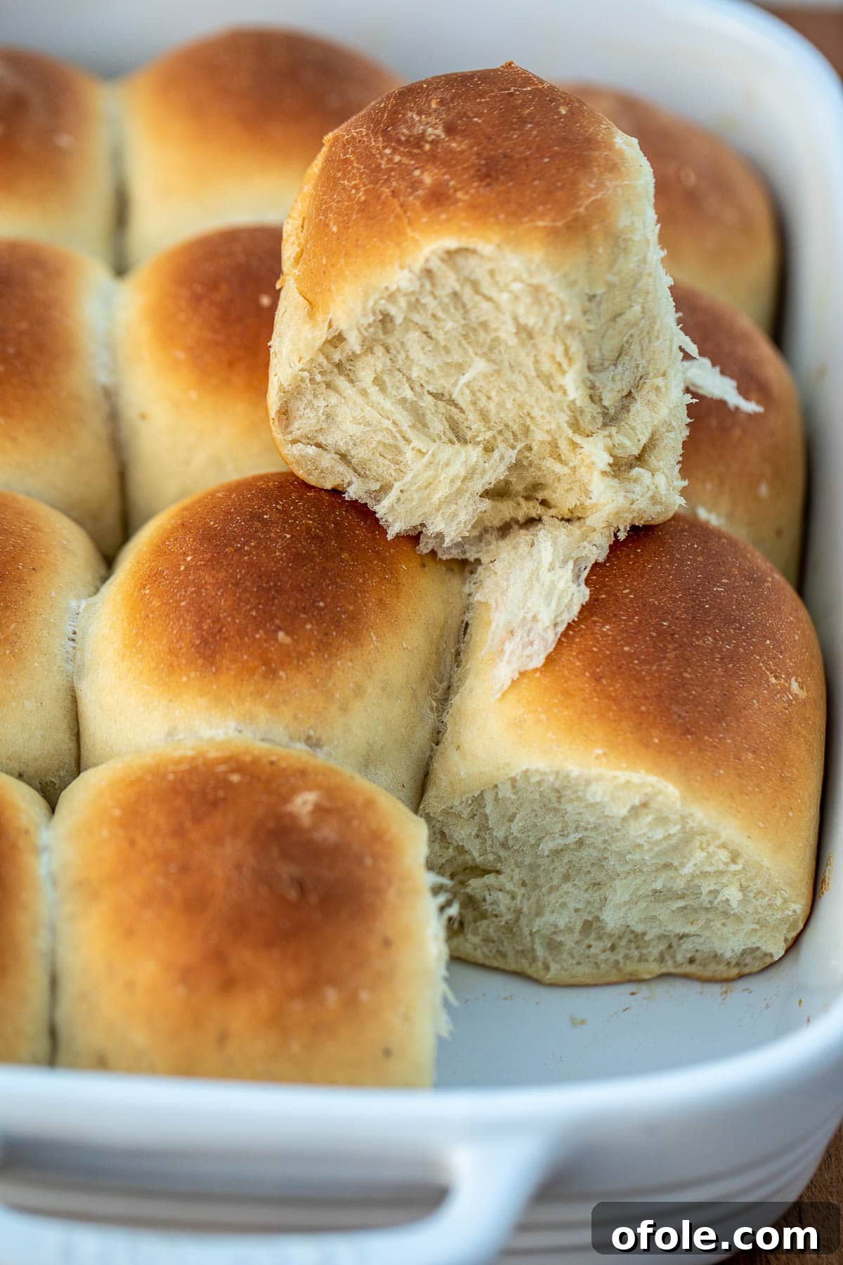 Golden Banana Bread Rolls 2 Golden brown fluffy banana bread rolls arranged in a baking pan, with one roll placed on top to highlight its soft texture