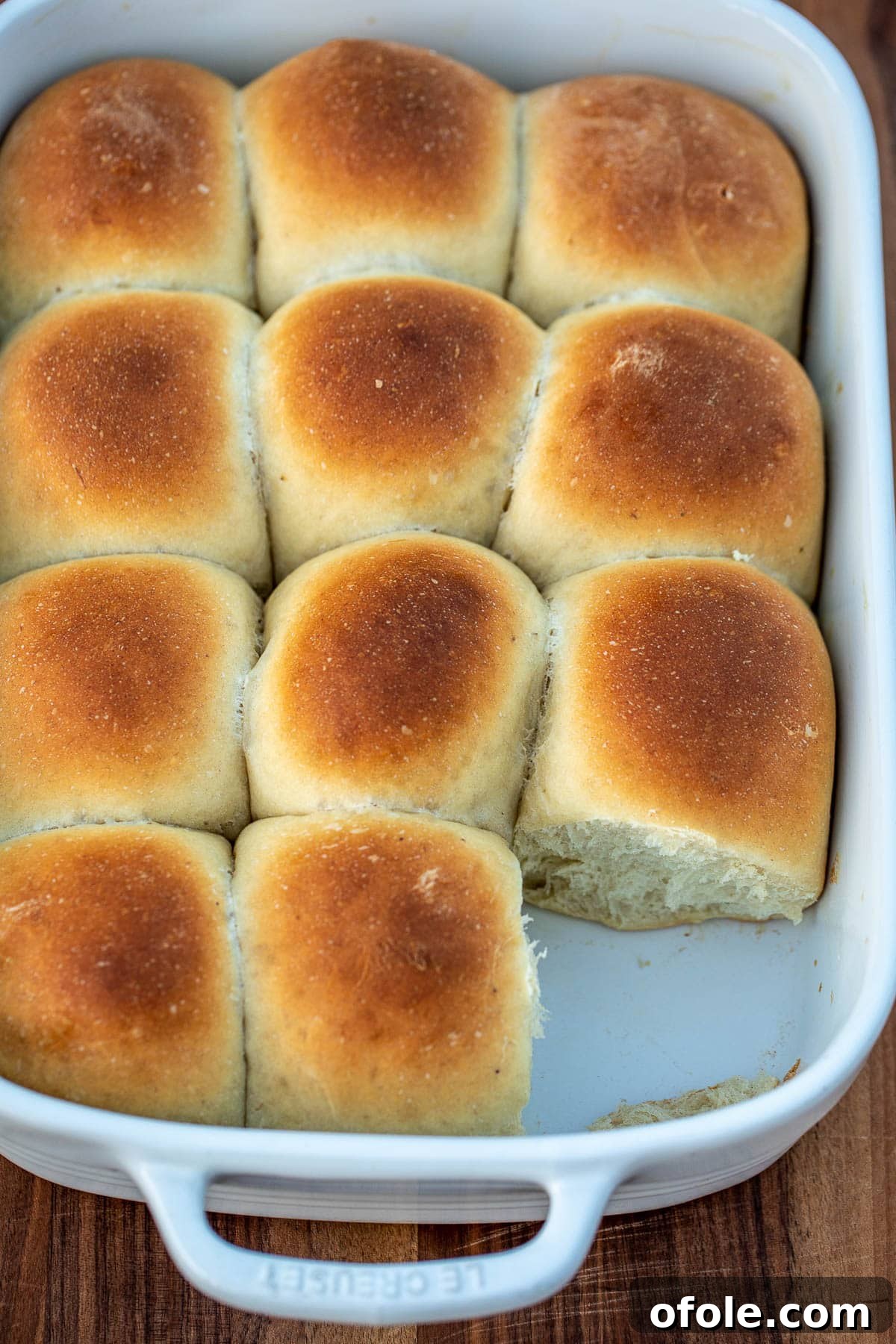 Golden Banana Bread Rolls 4 A pan full of freshly baked, golden brown banana bread rolls, with one roll removed to show the interior.