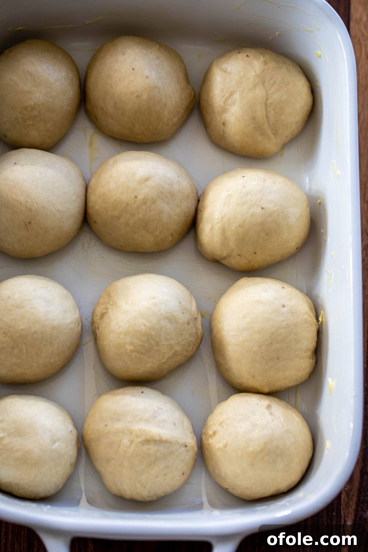 Golden Banana Bread Rolls 5 Unbaked banana bread dough balls neatly arranged in a greased baking dish, ready for their first rise.